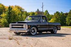 an old black pickup truck parked in a parking lot