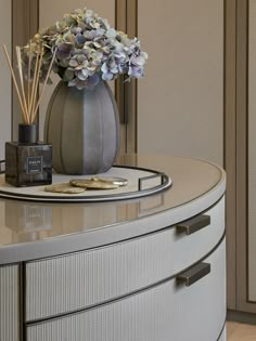 a vase filled with flowers sitting on top of a white dresser next to a candle