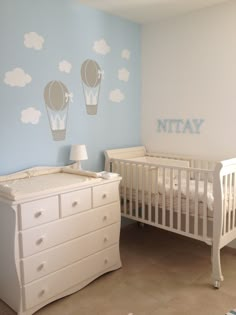 a baby's room with a crib, dresser and wall decals in the shape of hot air balloons