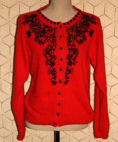 a red cardigan with black flowers on the front and back, sitting on a mannequin head