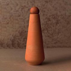 an orange vase sitting on top of a table next to a brown wall and floor