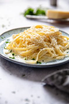 a plate of pasta with parmesan cheese on it sitting on a white table