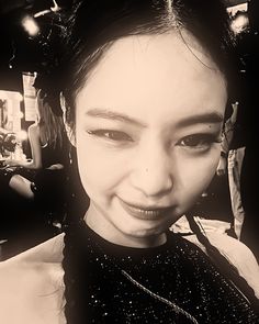 a black and white photo of a woman with her hair in a ponytail smiling at the camera