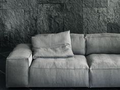 a gray couch sitting in front of a stone wall