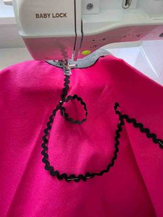 the sewing machine is working on the pink fabric that has been stitched into it