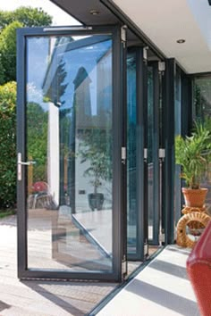 a red couch sitting on top of a wooden floor next to a tall glass door