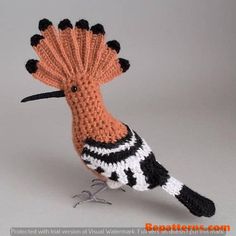 a crocheted bird with black, white and orange feathers