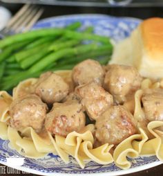 meatballs and noodles on a plate with asparagus in the background, ready to be eaten