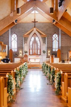 the inside of a church with rows of pews and flowers on each side of the aisle