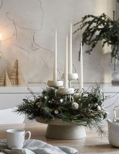 a candle holder with candles and greenery in it