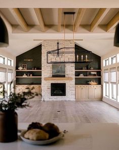 a large open living room with white walls and wood beams on the ceiling, along with a stone fireplace