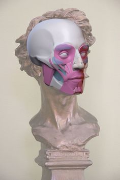 a white and pink mask sitting on top of a bust