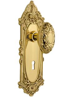 a golden door handle with an ornate design and keyhole on the front of it