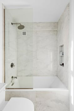 a white bathroom with marble walls and floor