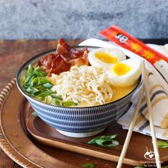 a bowl filled with ramen and eggs on top of a wooden tray