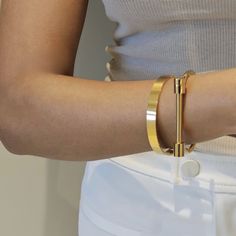 Our Screw Cuff Bangle in gold is the perfect stacking bangle. It features a high polished glossy design for a minimalist look. You can wear this minimalist bangle alone or stacked. Add a touch of sleek elegance to your outfit with our Screw Cuff Bangle. Its minimalist design is perfect for stacking with your other favourite accessories, or wearing alone for a sophisticated and effortless look. With its high polished finish, this bangle is sure to catch the eye and complete your style. This item Sleek Gold Jewelry Gift, Sleek Gold Jewelry For Gifts, Sleek Gold Jewelry As A Gift, Sleek Gold Metal Jewelry, Modern Metal Cuff Bracelet Tarnish Resistant, Minimalist Gold Metal Cuff Bracelet, Modern Gold-tone Gold Plated Cuff Bracelet, Sleek Adjustable Gold Jewelry, Modern Gold-tone Bangle