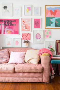 a living room filled with lots of pink and white art on the wall above a couch