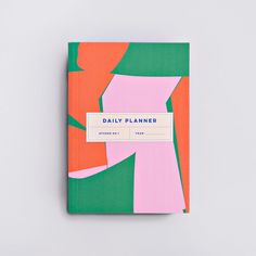 a pink and green notebook with a label on it that says daily planner in white