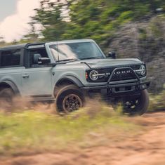 a grey truck driving down a dirt road