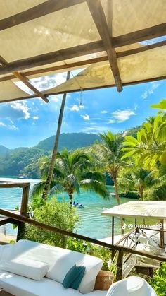 a white couch sitting on top of a wooden deck next to water and palm trees