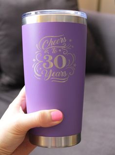 a woman holding a purple cup with gold lettering on it that says cheers to 30 years