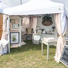 a white tent sitting on top of a grass covered field next to tables and chairs