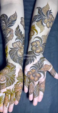 two hands with hendi tattoos on them and one hand painted gold, the other white