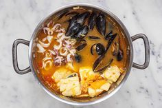 a pot filled with food on top of a white counter next to a marble table