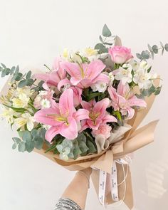 a bouquet of pink and white flowers in someone's hand on a white background