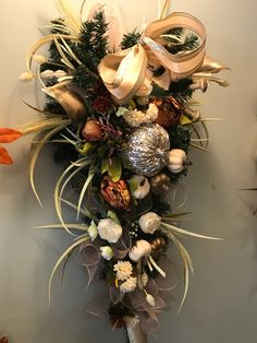 a christmas wreath hanging from the side of a wall with ornaments and greenery on it