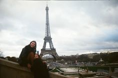 two women are posing in front of the eiffel tower