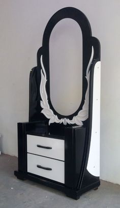 a black and white dressing table with mirror on it's side, in front of a wall