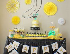 a table topped with cake and cupcakes covered in yellow paper fan decorating