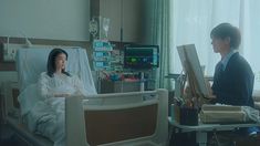 a woman sitting in a hospital bed next to a man who is looking at her