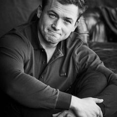 a black and white photo of a man sitting on a couch with his arms crossed