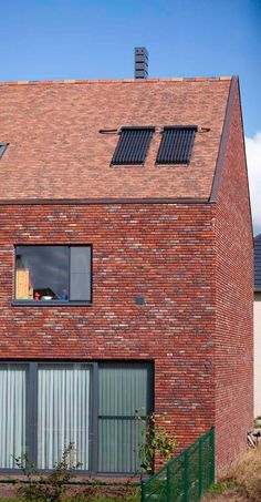 a red brick house with two windows and shutters