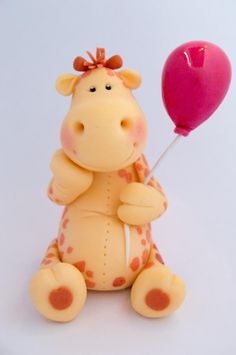 a toy giraffe holding a pink balloon on a white surface with no background