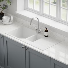 a white kitchen sink sitting under a window