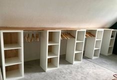 an empty room with several shelves and clothes hanging on hooks in the closet, all white