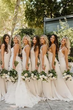 a group of women in white dresses standing next to each other with bouquets on their heads