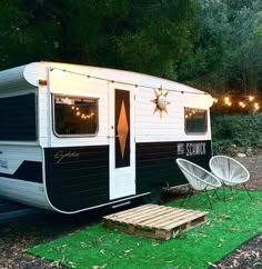 an rv is parked on the grass with lights strung from it's windows and door