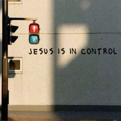 a traffic light with the words jesus is in control painted on it's side