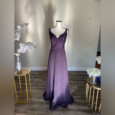 a dress is displayed on a mannequin next to a table with flowers and vases