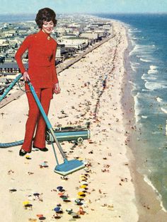 a woman in red is cleaning the beach with a mop and vacuum cleaner on her head