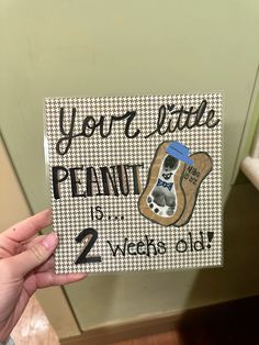 someone holding up a sign that says you're little peanut in 2 weeks old