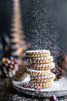 a stack of cookies sitting on top of a white plate covered in powdered sugar