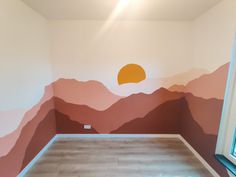 an empty room with mountains painted on the wall and a window in the corner,