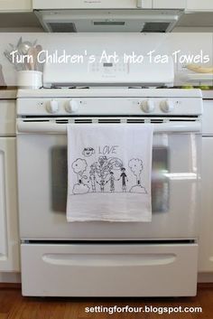 a tea towel hanging on an oven in a kitchen with the words turn children's art to tea towels