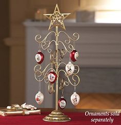 a gold christmas tree with ornaments on it and a red table cloth in the background