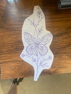 a piece of paper with a flower drawn on it sitting on a wooden table next to a pair of scissors